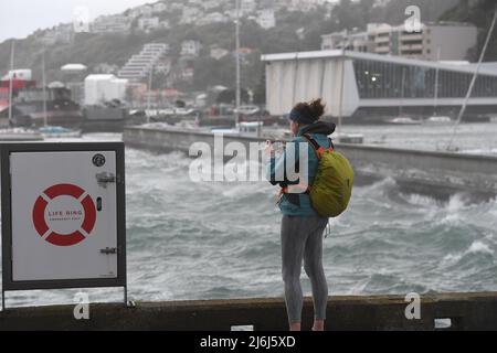 (220502) -- WELLINGTON, 2. Mai 2022 (Xinhua) -- das am 19. Januar 2021 aufgenommene Aktenfoto zeigt eine Frau, die Fotos macht, als riesige Wellen auf die Küstenlinie der Innenstadt von Wellington, Neuseeland, treffen. Die am Montag veröffentlichten neuen Daten zum Meeresspiegelanstieg zeigten, dass sich die Geschwindigkeit des Meeresspiegels in weiten Teilen Neuseelands verdoppeln wird, 20 bis 30 Jahre schneller als bisher erwartet. (Xinhua/Guo Lei) Stockfoto