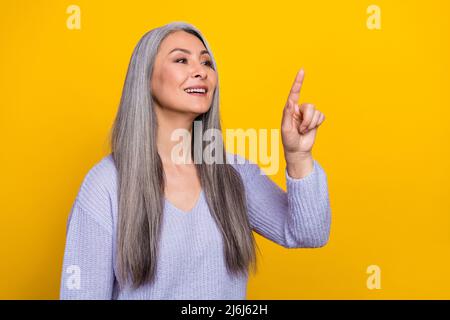 Foto von charmanten modernen jungen Rentner Dame mit moderner Technologie-Schnittstelle isoliert auf gelbem Hintergrund Stockfoto