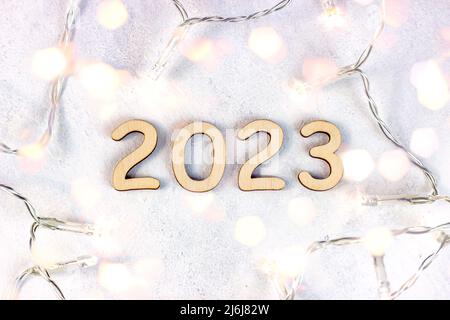 Holznummern 2023 Silhouette mit Weihnachtsbeleuchtung auf hellem Bokeh Hintergrund. Neujahrsbeginn Glückwünsche und Planungskonzept. Stockfoto
