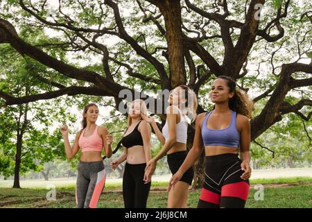 Glückliche junge multiethnische Frauen Teenager Freundgruppe Entspannen und Tanzen nach dem Training im Park am Wochenende Morgen. Junge Menschen Lifestyle-Konzept Stockfoto