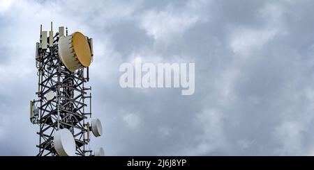 Bassdrum-ähnliche Mikrowellenantennen auf einem hohen Turm. 5G Mobilfunk für die Übertragung von Mobiltelefon- und Videodaten. Telekommunikationspunkt Stockfoto