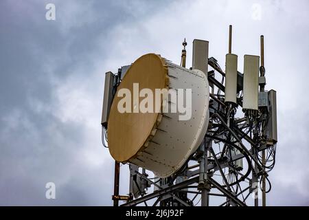 Bassdrum-ähnliche Mikrowellenantennen auf einem hohen Turm. 5G Mobilfunk für die Übertragung von Mobiltelefon- und Videodaten. Telekommunikationspunkt Stockfoto