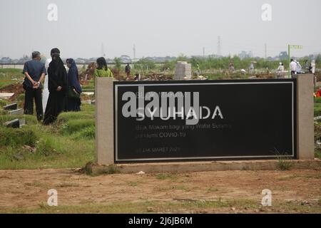 Eine Reihe von Bewohnern pilgern zu den Gräbern von Verwandten während der Feier des Eid Al-Fitr 1443 Hijri, am besonderen Grab für die Opfer von Covid-19, Rorotan Public Cemetery, Cilincing, Jakarta, Indonesien. Die diesjährige Eid al-Fitr-Feier wurde von einer Reihe von Muslimen genutzt, um Wallfahrten zu machen und für ihre Familien zu beten, die gemäß dem Covid-19-Protokoll begraben wurden. (Foto von Kuncoro Widyo Rumpoko/Pacific Press) Stockfoto