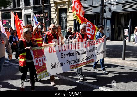 Die Demonstranten marschieren durch die Straßen, während sie während der Demonstration ein Transparent halten, auf dem ihre Meinung zum Ausdruck gebracht wird. Die Protestierenden nehmen am jährlichen 1. Mai (Tag der Arbeit) Teil, der den internationalen Tag der Arbeiter markiert. Stockfoto