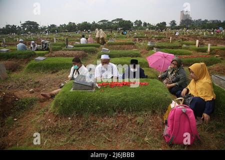 Eine Reihe von Bewohnern pilgern zu den Gräbern von Verwandten während der Feier des Eid Al-Fitr 1443 Hijri, am besonderen Grab für die Opfer von Covid-19, Rorotan Public Cemetery, Cilincing, Jakarta, Indonesien. Die diesjährige Eid al-Fitr-Feier wurde von einer Reihe von Muslimen genutzt, um Wallfahrten zu machen und für ihre Familien zu beten, die gemäß dem Covid-19-Protokoll begraben wurden. (Foto von Kuncoro Widyo Rumpoko/Pacific Press) Stockfoto