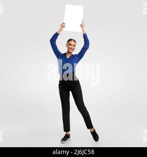 Geschäftsfrau hält leere weiße Werbetafel im Studio Stockfoto