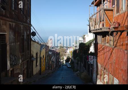 Valparaiso, Chile - Februar 2020: Schmale Straße in der Altstadt, die vom Hügel zum Meer führt. Alte Holzhäuser auf einem Hügel in nicht-touristischem Gebiet Stockfoto