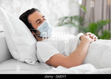 Kranker Mann in Gesichtsmaske, der im Bett an Viren leidet Stockfoto