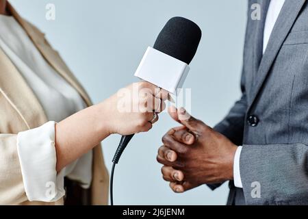 Seitenansicht Nahaufnahme einer jungen Frau, die das Mikrofon hält, während sie eine Geschäftsexpertin interviewt Stockfoto