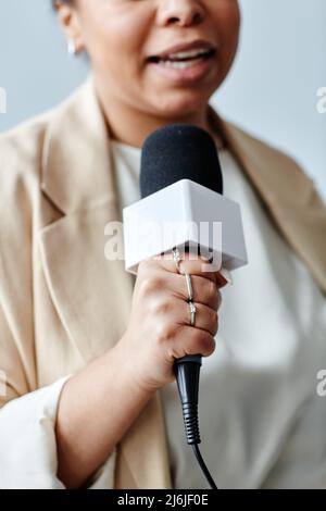 Vertikale Nahaufnahme einer Journalistin, die das Mikrofon hält, während sie Nachrichten berichtet Stockfoto