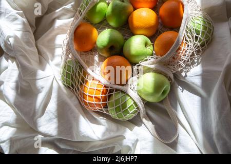 Saitenbeutel mit Früchten im Bett mit Sonnenstrahlen. Stockfoto