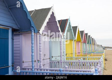 Bunt bemalte Strandhütten in einer Reihe in West Mersea, Mersea Island, Essex, Großbritannien Stockfoto