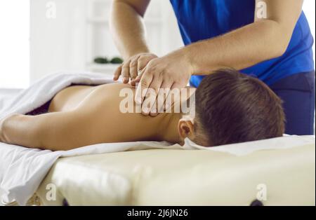 Masseur im modernen Gesundheitszentrum führt therapeutische Körpermassage für jungen Mann. Stockfoto