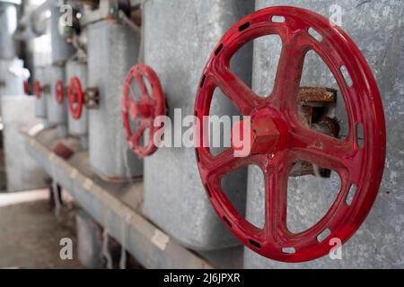 Rote Rohre und Ventilgriff-Rad an der abgebrochenen Ruine Stockfoto