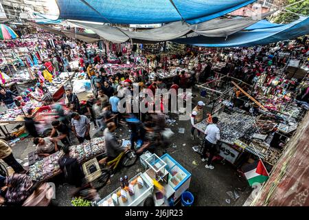 1. Mai 2022, Khan Youni, Gazastreifen, Palästina: Khan Younis, Gazastreifen, Palästina. 1.Mai 2022. Palästinenser kaufen auf einem lokalen Markt am Vorabend von Eid al-Fitr in der südlichen Stadt Khan Younis im Gazastreifen ein. Es ist Tradition für Muslime, am Ende des Ramadan Geschenke, neue Kleidung und Süßigkeiten zu kaufen, doch die Kaufkraft vieler Palästinenser in Gaza ist aufgrund der hohen Arbeitslosigkeit und der Armutsrate in der palästinensischen Enklave begrenzt (Bildquelle: © Yousef Mohammad/IMAGESLIVE via ZUMA Press Wire) Stockfoto