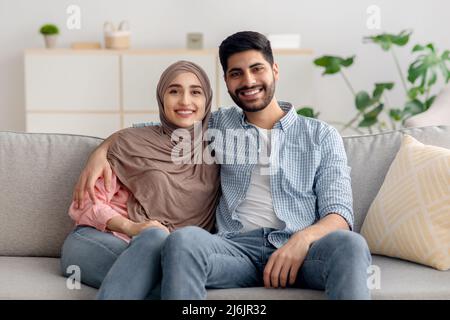 Glückliches Muslimisches Familienpaar Sitzt Zusammen Und Umarmt Zu Hause Stockfoto
