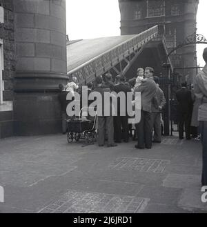 1953, historisch, Menschen versammelten sich in einem der Türme auf Tower Bride, um die Mitte der Brücke zu beobachten, die angehoben wird, London, England, Großbritannien. Eine der berühmtesten Attraktionen Londons, die kombinierte Bascule- und Hängebrücke überquert die Themse und wurde 1894 eröffnet. Stockfoto