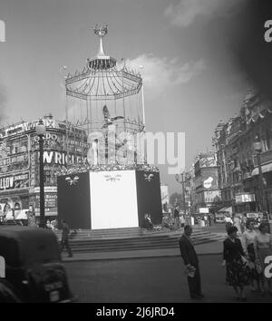 1953, historisch, Queens' Cornation, Piccadilly Circs, London, England, Großbritannien. Das Bild zeigt die Shaftesbury Memorial Foundation, besser bekannt als Eros Eros, die mit einem eisernen Vogelkäfig bedeckt ist. Es wurde von Sir Hugh Casson als Gehege entworfen, um es vor den großen Menschenmengen zu schützen, die in die Stadt kamen, um die Krönung von Königin Elizabeth II. Zu feiern Stockfoto