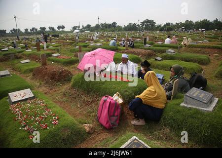 Eine Reihe von Bewohnern pilgern zu den Gräbern von Verwandten während der Feier des Eid Al-Fitr 1443 Hijri, am besonderen Grab für die Opfer von Covid-19, Rorotan Public Cemetery, Cilincing, Jakarta, Indonesien. Die diesjährige Eid al-Fitr-Feier wurde von einer Reihe von Muslimen genutzt, um Wallfahrten zu machen und für ihre Familien zu beten, die gemäß dem Covid-19-Protokoll begraben wurden. (Foto von Kuncoro Widyo Rumpoko/Pacific Press/Sipa USA) Stockfoto