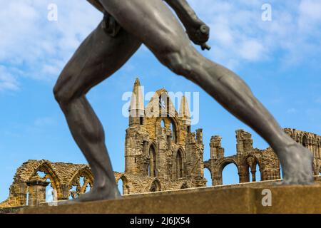 Whitby Abbey durch die Beine der Borghese Gladiator Statue in Whitby, Yorkshire, Großbritannien im April Stockfoto