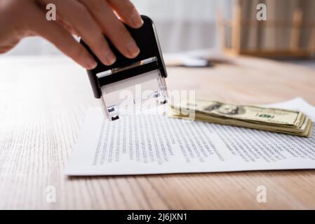 Beschnittene Ansicht des Anwalts, der in der Nähe von Kontrakt- und Dollar-Banknoten Stamper hält Stockfoto