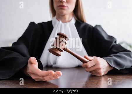 Teilansicht eines Richters in schwarzem Mantel, der Gavel hält, während er am Schreibtisch sitzt Stockfoto