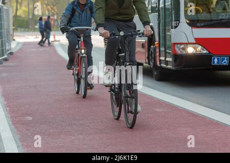 Radfahrer auf der roten Fahrradstraße neben dem Stadtbus Stockfoto