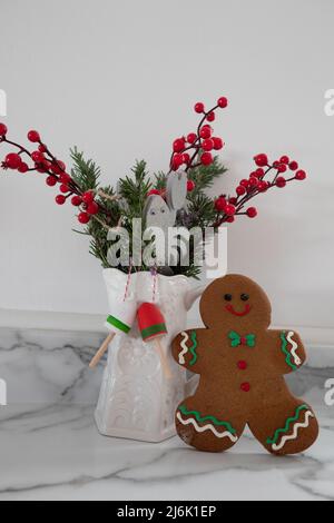 Display mit Lebkuchenmännchen-Cookie mit weihnachtlichen roten Beeren, weißen Krug Hummer und Boje auf hellem Hintergrund Stockfoto