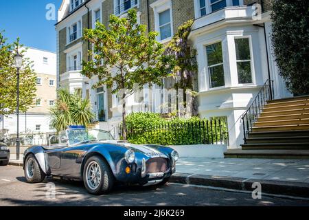 London - ein AC Cobra Sportwagen, der vor einer attraktiven Straße mit Reihenhäusern geparkt wurde Stockfoto