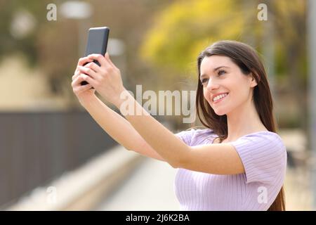 Glücklicher Teenager, der Selfie mit dem Smartphone in einem Park macht Stockfoto