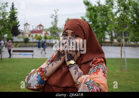 2. Mai 2022, Athen, Griechenland: Eine Frau nach Beendigung des Eid al-Fitr-Gebets in der Moschee steht für ein Foto, auf dem ihre Hände mit Henna geschmückt sind, während im Hintergrund eine griechisch-orthodoxe Kirche zu sehen ist. Gläubige versammeln sich, um Eid al-Fitr-Gebet in der offiziellen Moschee der griechischen Hauptstadt durchzuführen. (Bild: © Dimitris Aspiotis/Pacific Press über ZUMA Press Wire) Stockfoto