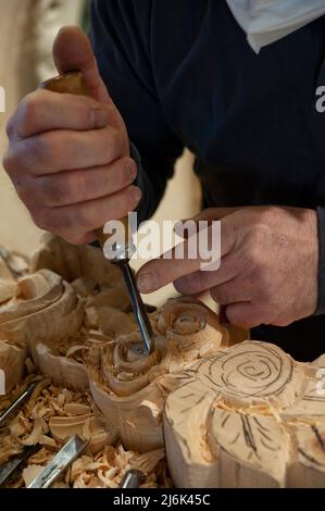Meister des Holzschnitzers bei der Arbeit. Holzspänen, Furchen und Meißel auf der Werkbank. Stockfoto