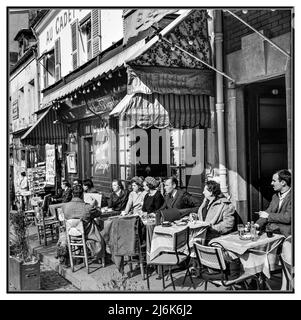 Paris Montmartre Cafe Restaurant aus den 1960er Jahren, Terrasse im Freien mit Tischen und Getränken. Straßenkünstler zeichnet ein Porträt am Tisch Place du Tertre Montmartre Paris Frankreich 1965 Willem van de Poll Fotograf Stockfoto