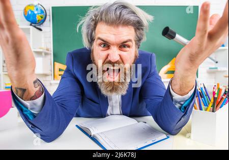 Wütend Bartlehrerin im Klassenzimmer sitzt am Schreibtisch. Zurück zur Schule. Lernen, Bildung. Lehrertag. Stockfoto