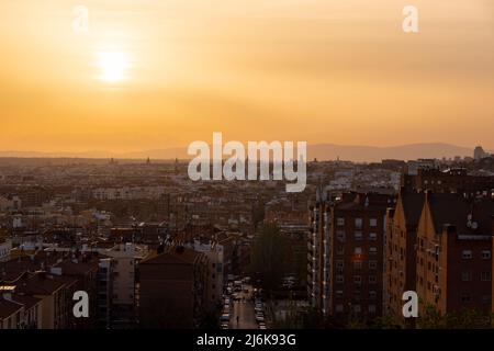 Ein herrlicher, warmer Sonnenuntergang über der Skyline von Madrid mit Blick auf die Bergkette, Sierra de Guadarrama am Horizont, von las siete tetas aus gesehen Stockfoto