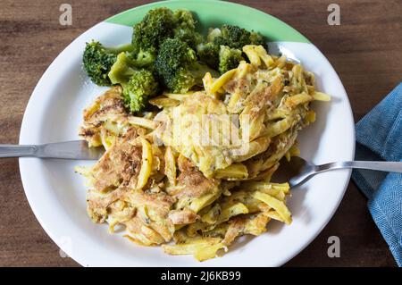 Teller mit pommes Frites, zubereitet mit Omelett, serviert mit Brokkoli auf einem Teller mit grünem Detail Stockfoto