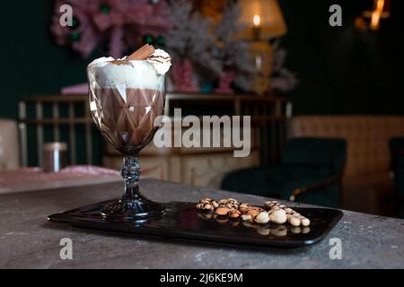 Süßer Milchshake mit Creme und Zimt in einem Glas. Stockfoto