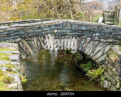 Fell Foot Bridge - eine alte Schiefersegmentbrücke mit einem Bogen über den Fluss Brathay, Little Langdale, English Lake District, Cumbria, England, VEREINIGTES KÖNIGREICH Stockfoto