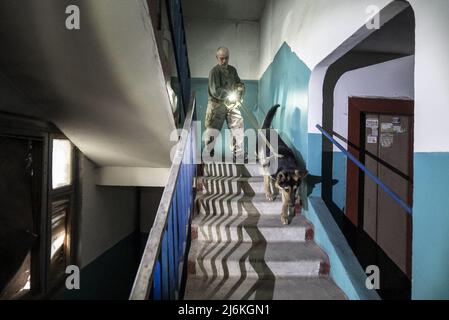 Charkiw, Ukraine. 02.. Mai 2022. Sasha Zolotov, 55, früher im Militär, geht am Montag, den 2. Mai 2022, mit seinem deutschen Schäferhund „Krokodilhund“ die Treppe seines Wohnhauses in der Nähe der russischen Grenze in Charkow, Ukraine, hinunter. Zolotows Wohnung wurde zweimal getroffen, nur wenige Wochen auseinander. Die Wohnung brannte ab und alles, was er übrig hatte, waren die Kleidung, die er trug, und sein Reisepass. Zolotov lebt jetzt im Keller gedreht Bombenschutz. Foto von Ken Cedeno/UPI Credit: UPI/Alamy Live News Stockfoto