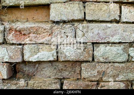 Textur einer alten Wand, eine Wand aus beschädigten farbigen Ziegel, mit Mängeln im Putz, Spinnweben, Hintergrund, Tapete für Projekte Stockfoto