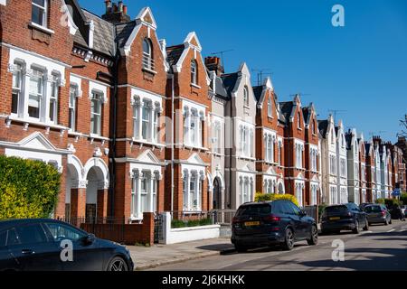 London - April 2022: Eine attraktive Straße aus historischen Backsteinterrassenhäusern in Shepherds Bush, Kensington im Westen Londons Stockfoto