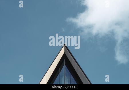 Abstraktes Architekturbild eines dreieckigen Gebäudes gegen Einen blauen Himmel mit Wolken und Kopierraum Stockfoto