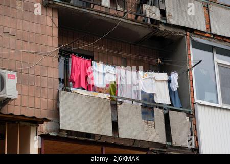 Die Wäsche an der Wäscheleine wird auf dem alten kaputten Balkon getrocknet. Der Balkon eines mehrstöckigen Wohnhauses. Die armen Gegenden der Stadt erfordern ein Hom Stockfoto