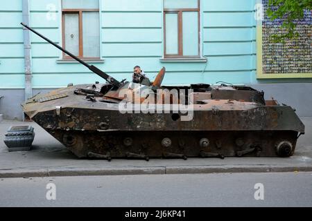 Kiew, Ukraine - am 02. Mai 2022 Untersucht Ein Mann einen zerstörten russischen Panzer, der am Straßenrand geparkt ist und vom ukrainischen Militär in der Region Kiew zerstört wurde. Russland marschierte am 24. Februar 2022 in die Ukraine ein und löste damit den größten militärischen Angriff in Europa seit dem Zweiten Weltkrieg aus Stockfoto