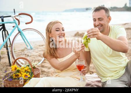 Reifes Paar, das am Sommertag in der Nähe des Meeres picknickt Stockfoto