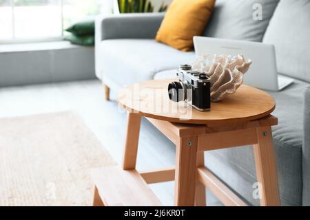 Holztreppe mit Fotokamera in der Nähe des Sofas im Inneren des Wohnzimmers Stockfoto