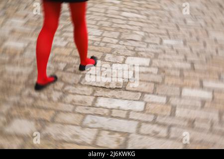 Special Effects Bild von Frauen Füße und Beine tragen rote Strümpfe, schwarze Schuhe und gehen auf Pflastersteinen. Stockfoto