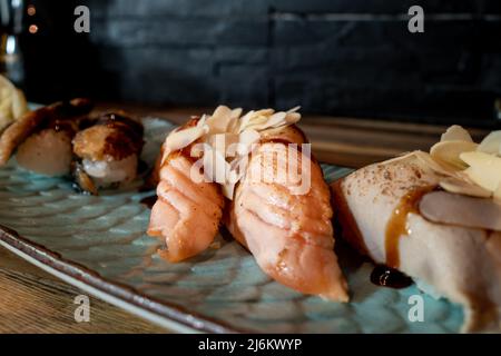 Selektive Konzentration auf gebratenen Lachs-Nigiri und ein Set gebratenes Nigiri-Sushi. Stockfoto