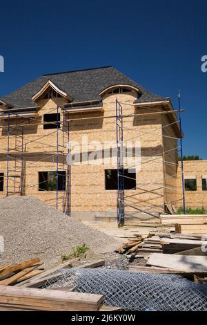 Unfertiges luxuriöses Haus mit nuanciertem dunkelbraunen Asphaltschindeln Dach. Stockfoto