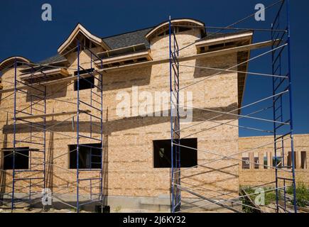 Unfertiges luxuriöses Haus mit nuanciertem dunkelbraunen Asphaltschindeln Dach. Stockfoto